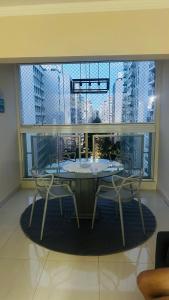 a table and chairs in a room with a large window at Joia Da Pitangueiras in Guarujá