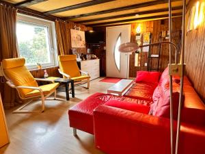 a living room with a red couch and yellow chairs at Bijouswiss " Yellow House" in Oberterzen