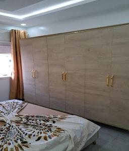 スースにあるMagnifique Appartement S+1のベッドルーム1室(大型ベッド1台、木製キャビネット付)