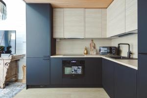 a kitchen with black cabinets and a blue wall at Glass Ceiling Suite Kipinä in Sirkka