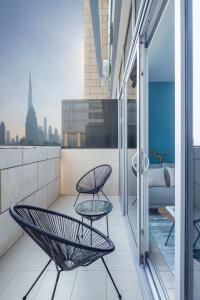 balkon z 2 krzesłami i kanapą w budynku w obiekcie Silkhaus elegant studio with Burj Khalifa view and balcony w Dubaju