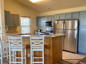 une cuisine avec un réfrigérateur en acier inoxydable et des tabourets blancs dans l'établissement Salty Root-Southern Shores Beauty-Free Pool Heat April & May, à Kitty Hawk