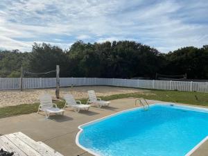 une piscine avec chaises longues et un panier de volley-ball dans l'établissement Salty Root-Southern Shores Beauty-Free Pool Heat April & May, à Kitty Hawk