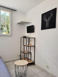 a room with a table and a chair and a television at Abrivado Appartements meublés dans une grande propriété en rez de jardin in Aimargues