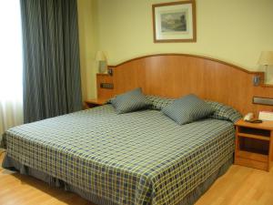 a bedroom with a bed with a checkered blanket at II Castillas Madrid in Madrid