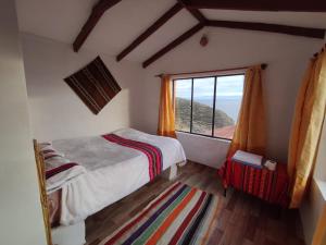 um quarto com uma cama e uma grande janela em INTI WASI LODGE em Comunidad Yumani