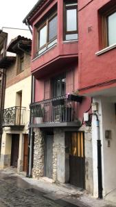 a red building with a balcony on a street at donibane 20 Orduña in Orduña