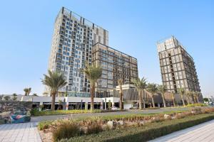 due edifici alti con palme di fronte a una strada di Silkhaus Luxury 1BDR Dubai Hills Pool & Gym a Dubai