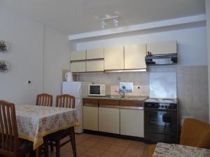 eine Küche mit einem Tisch, einem Herd und einer Mikrowelle in der Unterkunft Apartments Sonja in Opatija
