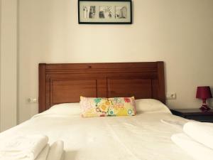 a bed with a wooden headboard and a pillow on it at Apartamentos San Pelayo in Cangas de On&iacute;s