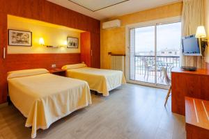 a hotel room with two beds and a balcony at Hotel Checkin Trave in Figueres