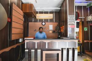 Un uomo in piedi dietro un bancone in un ristorante di Hotel Vardhmaan Inn a Nuova Delhi
