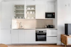 a kitchen with white cabinets and a sink and a microwave at Blueground Dreta de lEixample nr pl catalunya BCN-42 in Barcelona