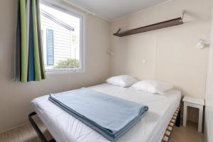 Camping maeva Club Royal Océan في Saint-Sulpice-de-Royan: سرير أبيض في غرفة بها نافذة