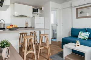 a kitchen and living room with a blue couch and stool at San Antonio mobile homes in Biograd na Moru