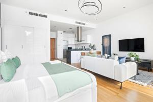 een witte slaapkamer met een groot bed en een bank bij Silkhaus cozy Studio at Al Bandar Marina with gym in Abu Dhabi