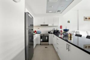 La cuisine est équipée de placards blancs et d'un réfrigérateur noir. dans l'établissement Silkhaus Luxury studio in Saadiyat Island, à Abu Dhabi