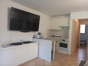 uma cozinha com uma grande televisão de ecrã plano na parede em Les Hauts du Golf Rez de jardin Piscine Tennis em Saint-Raphaël