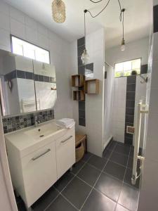 uma casa de banho branca com um lavatório e um chuveiro em La terrasse Majorelle. em Le Passage