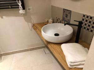 ein Badezimmer mit einem weißen Waschbecken auf einer Holztheke in der Unterkunft Locus Pendinelli Trani in Trani