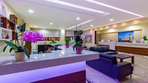 a lobby with a waiting area with purple flowers at Paleos Hotel Apartments in Ialyssos