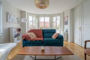 Una sala de estar con un sofá azul y una mesa. en Le cocon d'Emma, terrasse, jardin et élégance dans maison de Maître, en Estrasburgo 19 fotos más