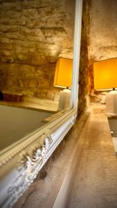 Un espejo en una pared junto a una mesa con lámparas. en Chiama Grotta Ride the Beauty Assisi, en Asís