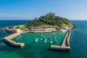 an island with boats in the water with a castle at Cosy 2 Bedroom Apartment near Seafront in Penzance