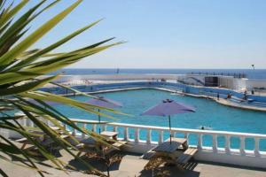 a large swimming pool with chairs and an umbrella at Cosy 2 Bedroom Apartment near Seafront in Penzance
