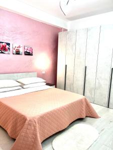 1 dormitorio con 1 cama con pared de color rosa en Stefy's House, en Scalea