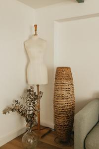 a mannequin on a stand next to a vase and a lamp at Mercerie de Denise in Le Bourg-Dun
