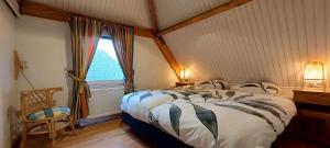 1 dormitorio con cama, ventana y silla en Luxe 4p huis met SAUNA bij Grevelingenmeer!, en Herkingen
