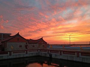 um pôr-do-sol sobre um edifício com uma massa de água em Ba Ba Guan Hai Ancient House B&B em Jinsha