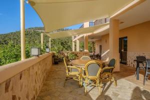 an outdoor patio with a wooden table and chairs at Casa en Cala Vadella con piscina y vistas al mar in Sant Josep de sa Talaia