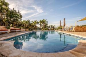 a swimming pool in a resort with palm trees at Casa en Cala Vadella con piscina y vistas al mar in Sant Josep de sa Talaia