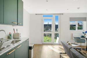倫敦的住宿－LiveStay - Modern Apartments on Acton Lane，厨房配有绿色橱柜和桌椅