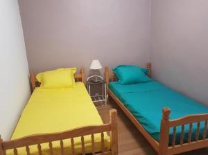 duas camas num pequeno quarto com amarelo e azul em Appartement de 3 chambres avec wifi a Vayrac em Vayrac