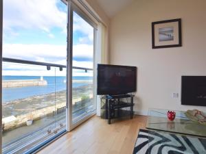 a living room with a television and a large window at 2 Bed in Seahouses CN198 in Seahouses