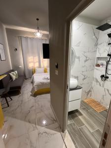 a bedroom with a bed and a bathroom with marble floors at Jonian Boutique Hotel in Sarandë