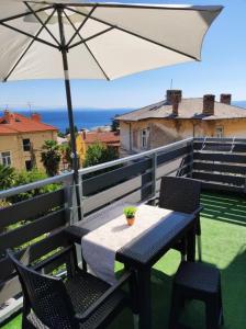 a table and chairs with an umbrella on a balcony at Ellena Sunshine in Opatija