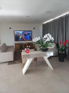 a living room with a couch and a table with flowers at Pousada Martins in São Mateus