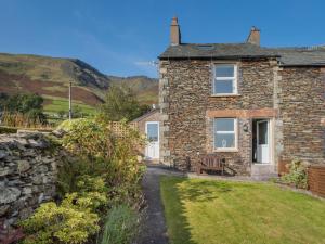 a stone house with a bench and a stone wall at 3 Bed in Keswick oc-sz227 in Threlkeld