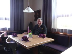 Ein Mann, der an einem Tisch in einem Restaurant sitzt. in der Unterkunft Hotel-Restaurant Zum Goldenen Hahnen in Markgröningen