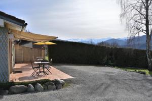 um pátio com uma mesa e um guarda-chuva ao lado de uma casa em Maisonnette à la campagne Ariège em Saint-Girons