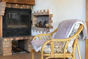 a wicker chair sitting in front of a fireplace at Maisonnette à la campagne Ariège in Saint-Girons
