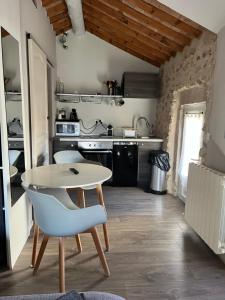a small kitchen with a white table and a chair at Petit studio Le Pigeonnier à 5 mn de Lourmarin in Puyvert