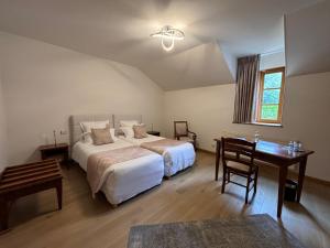 een slaapkamer met 2 bedden, een tafel en een bureau bij Hotel Le Manasses in Curtil-Vergy