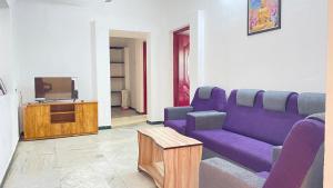 a living room with a purple couch and a tv at White House - 2BHK - Esha Apartment in Coimbatore