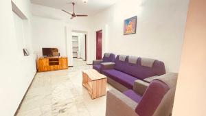 a living room with a purple couch and a tv at White House - 2BHK - Esha Apartment in Coimbatore +3 photos