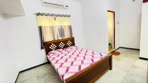 a bedroom with a bed with a pink comforter at White House - 2BHK - Esha Apartment in Coimbatore